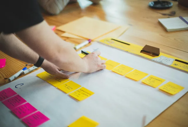 A person mapping ideas with colourful sticky notes around a table